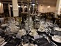 Image of a formal round dinner table with black tablecloth, dishware, glasses and candlestick holder in the centre