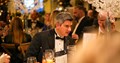 male guest wearing  a black tie evening suit sat at dining table talking with other award evening attendees